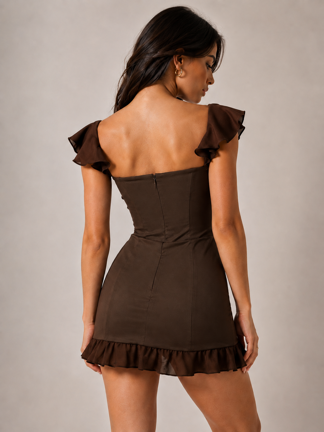 Rear view of the deep-brown corset mini dress, showing its open back, ruffle sleeves and ruffled hem.