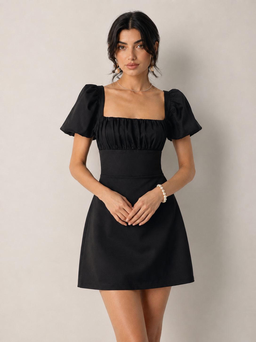 Front view of a black square-neck mini dress with short puff sleeves and a fitted waist.
